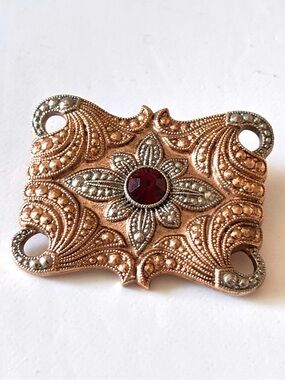 Rose gold and silver toned with a ruby colored stone brooch